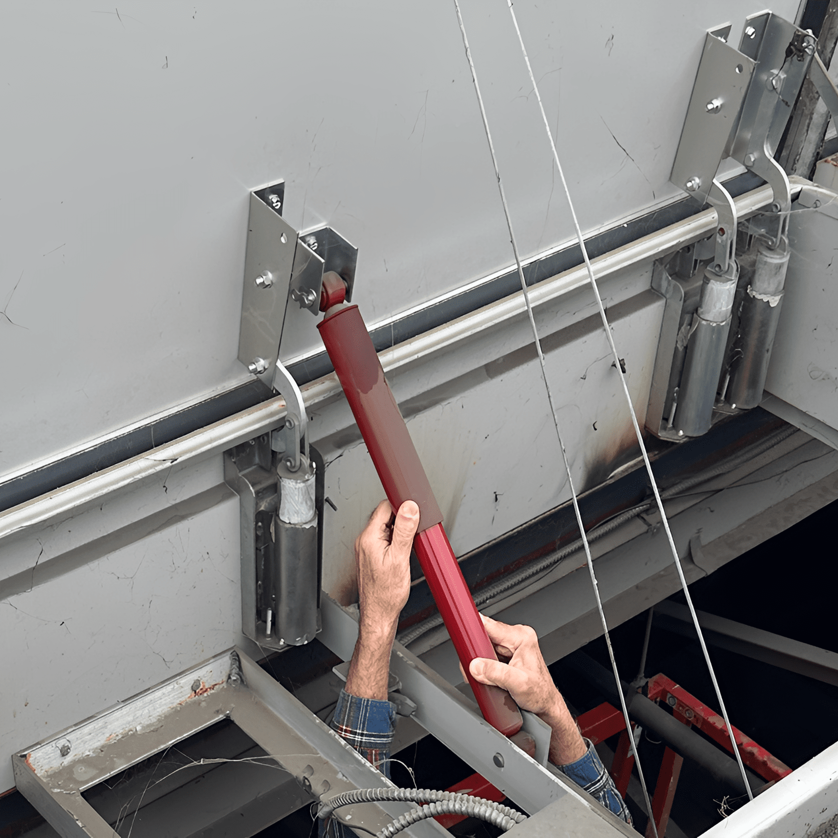Person installing a red component on machinery.